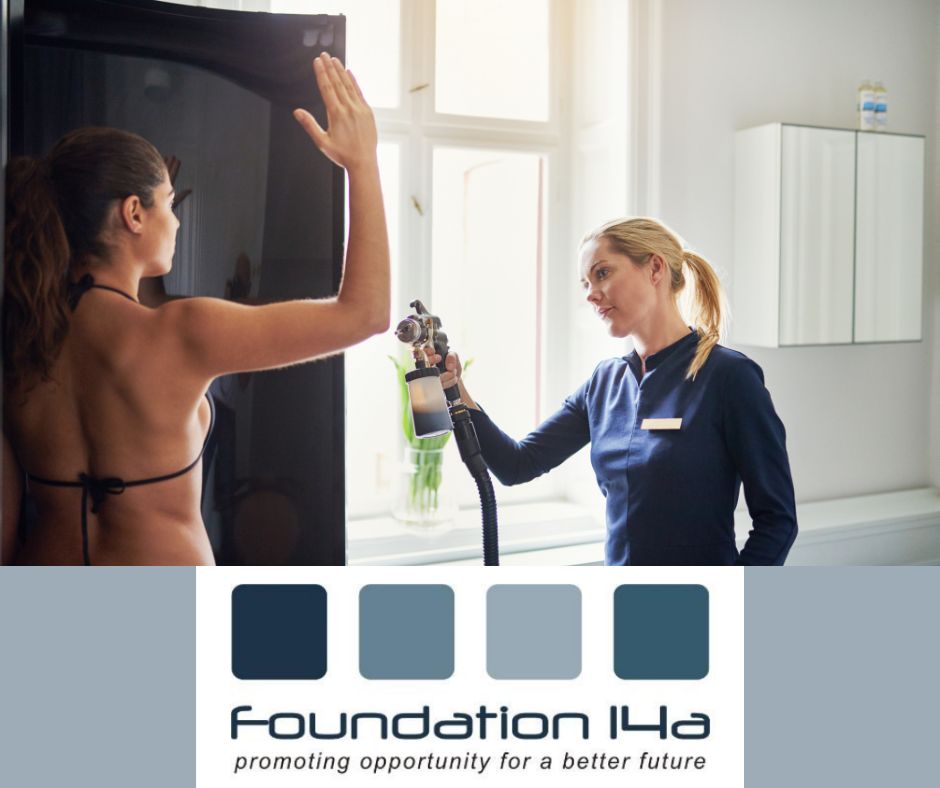 Cosmetic Spray Tanning Course - A lady in a bikini stands in a tanning booth with her arm raised so beautician can spray tan under arm